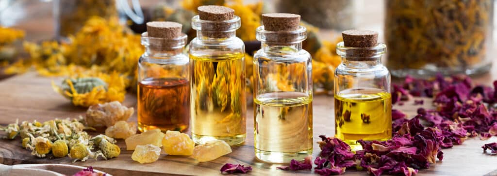 bottles of liquids on a table with flower petals surrounding them